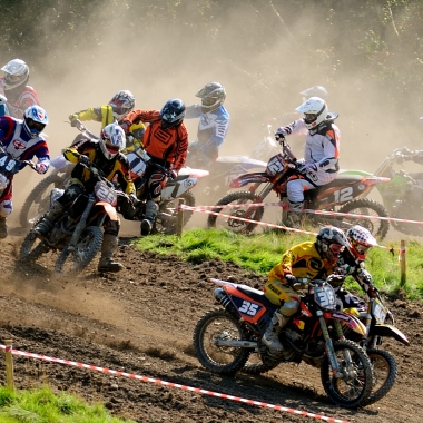 Photo d'une course de moto-cross. Accélération plein gaz à la sortie du premier virage après le départ